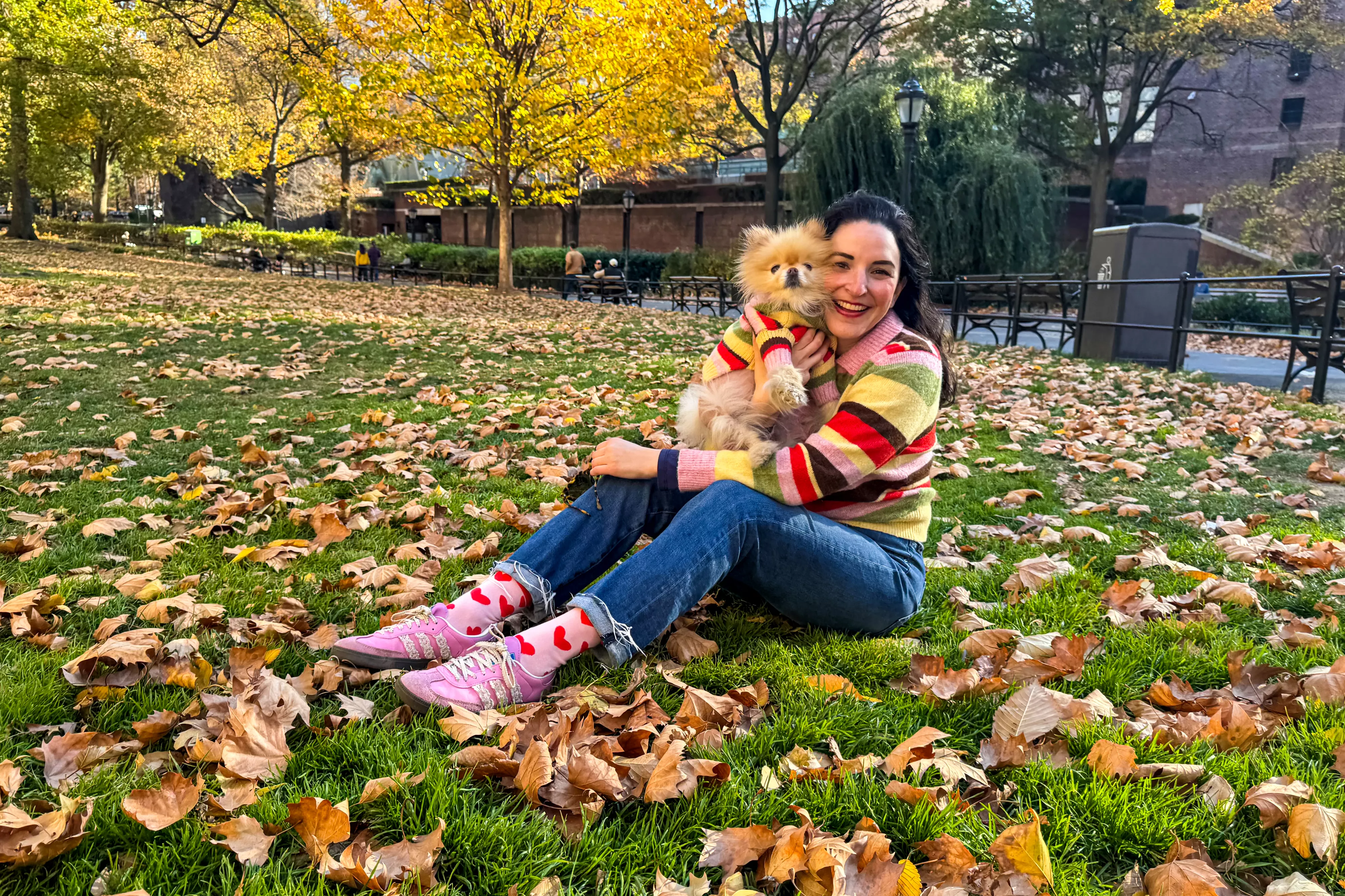 Woman with small dog wearing matching sweaters in a park