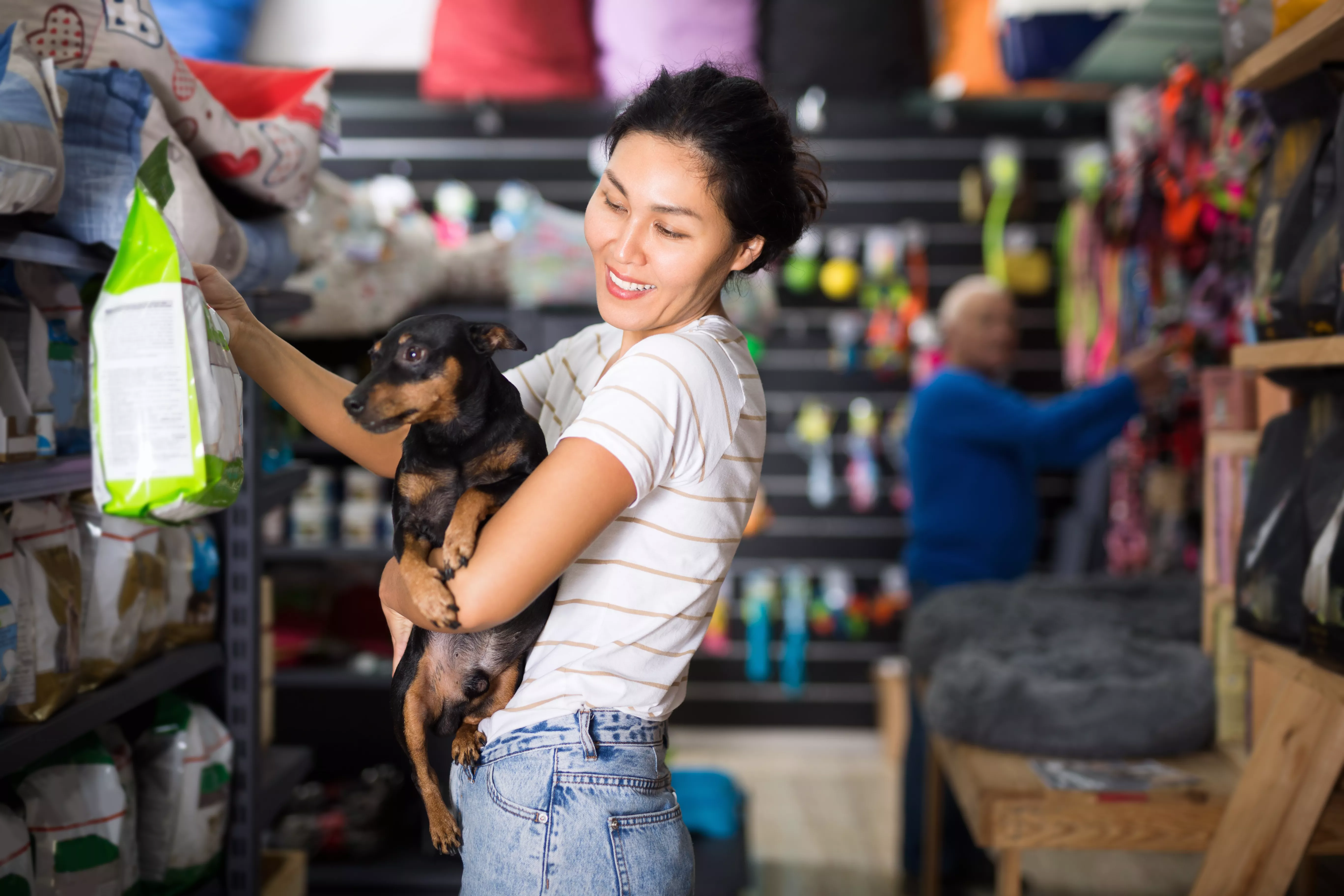 woman and dog choose dog food at pet store