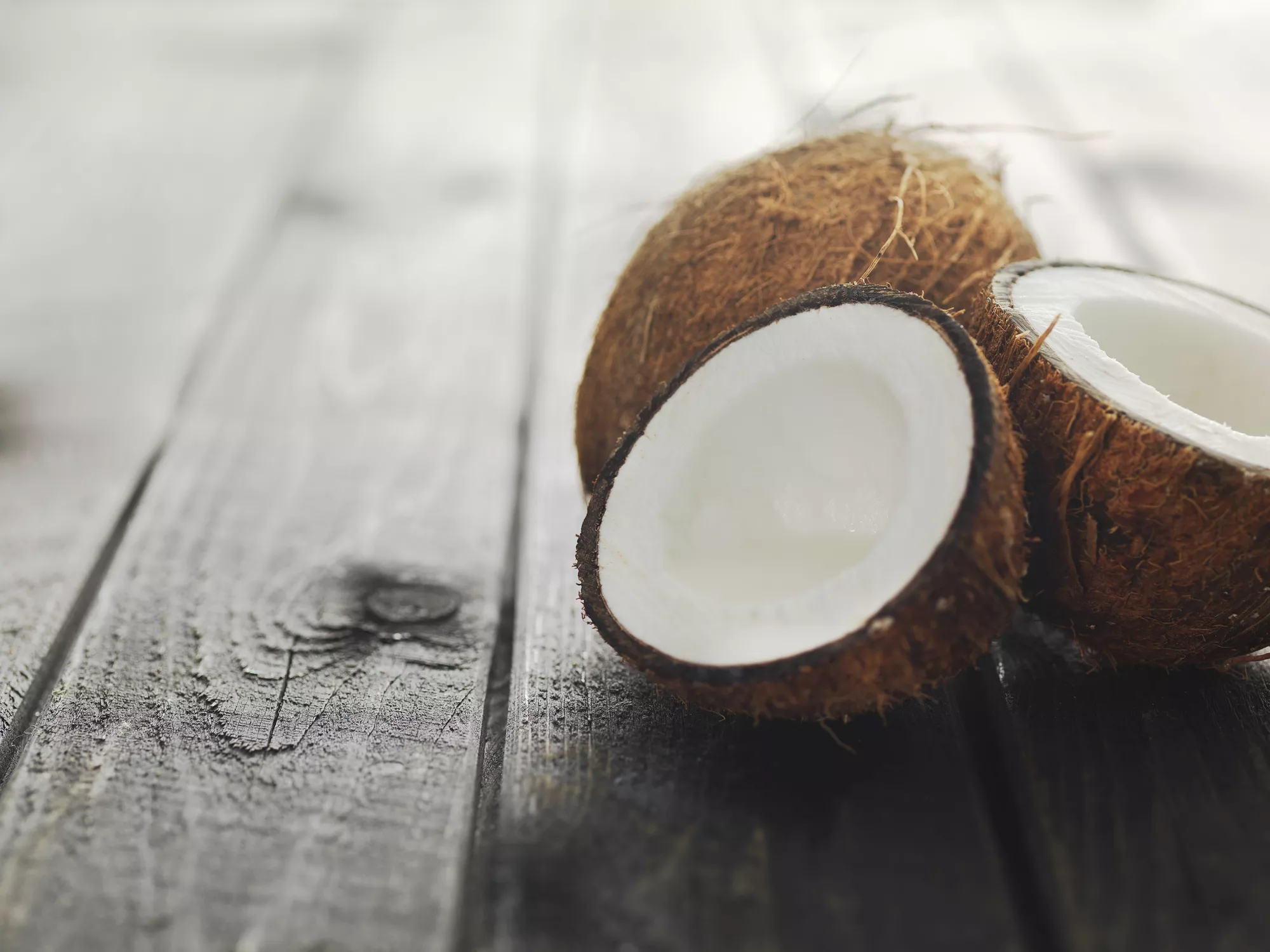 Two coconuts on wood surface, one cut in half